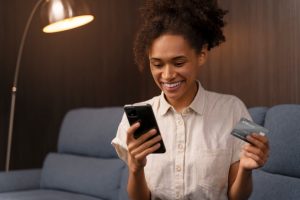 Jovem acessando site no celular após aprender como comprar passagem de ônibus pela internet.