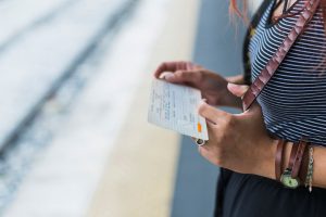 Mulher jovem com passagem de ônibus nas mãos após alterar a titularidade.