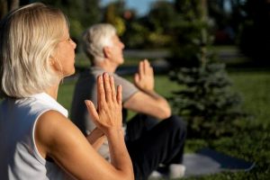 Casal de idosos fazendo yoga em um retiro de turismo terapêutico.